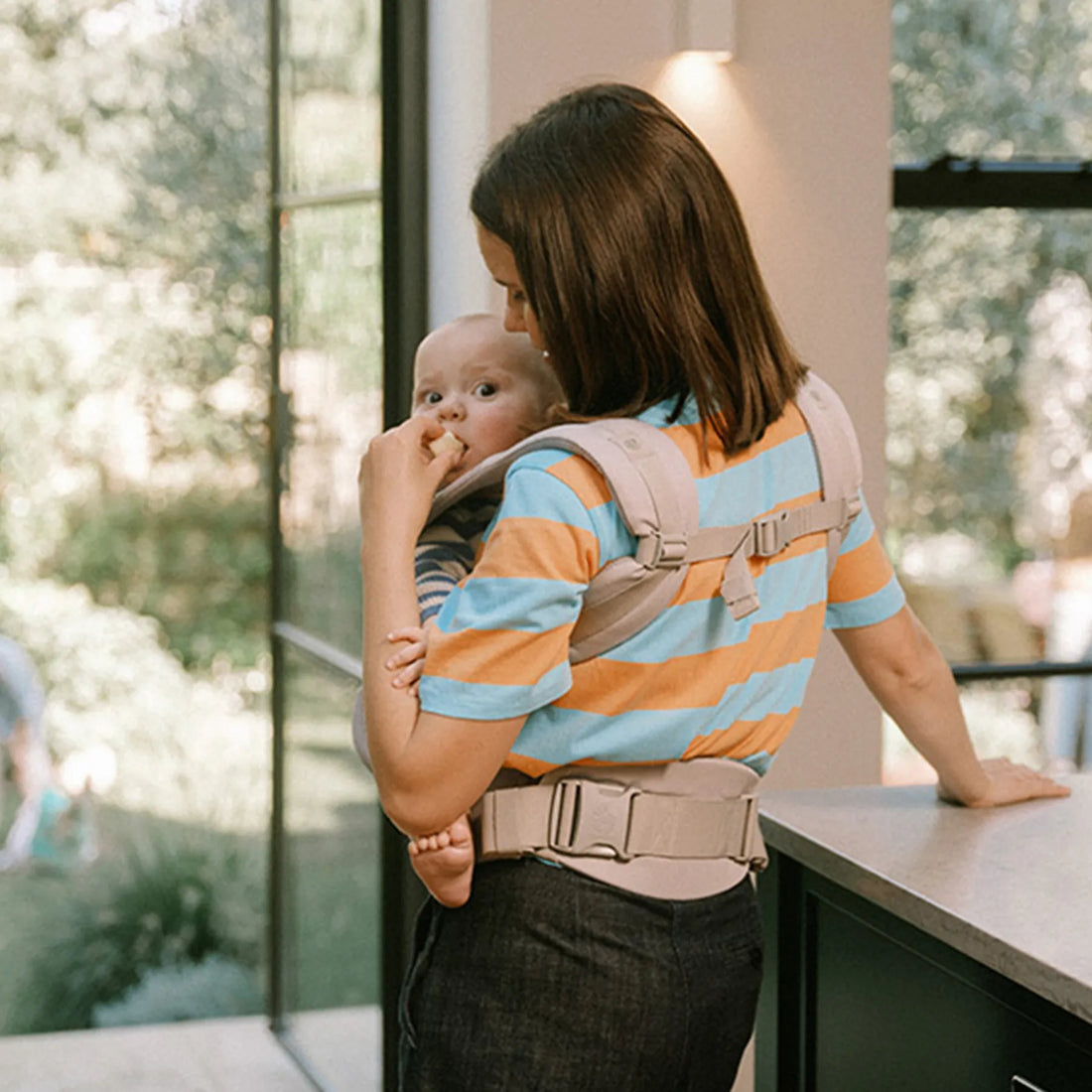 Frau, die ein Baby in einer Babytrage hält