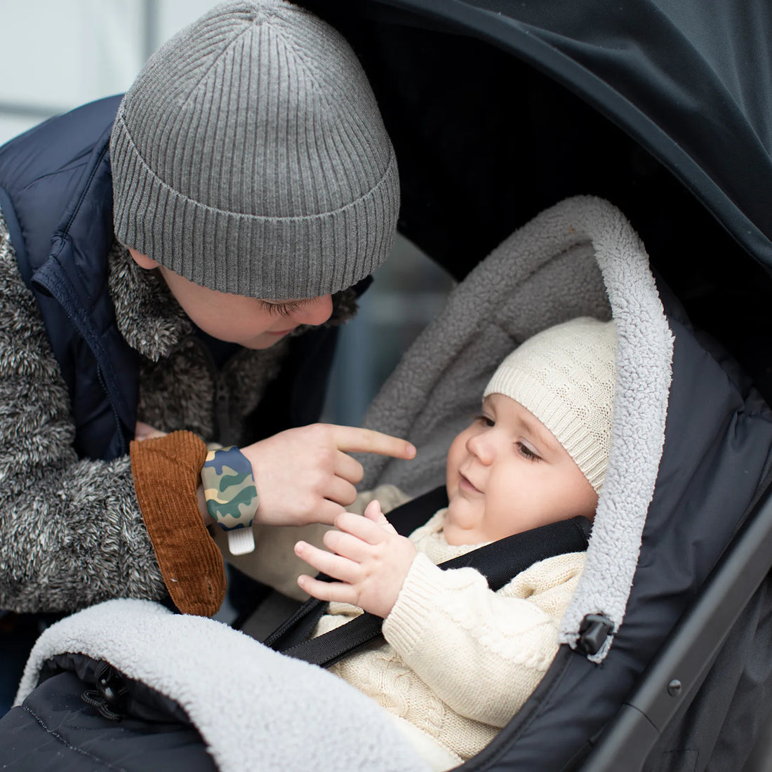 Ein Kind spielt mit einem Baby im Kinderwagen