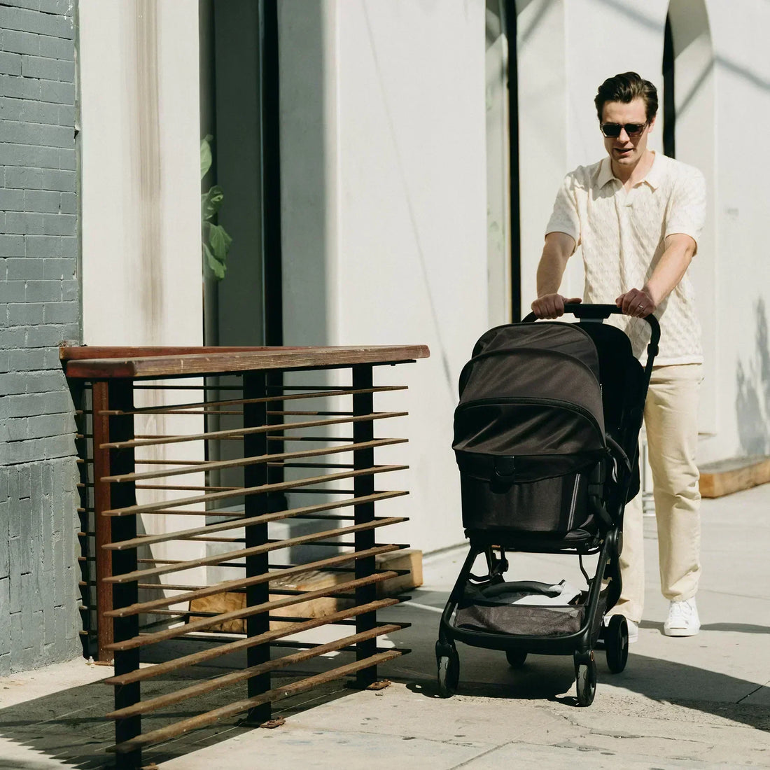 Ein Mann schiebt draußen einen schwarzen Kinderwagen