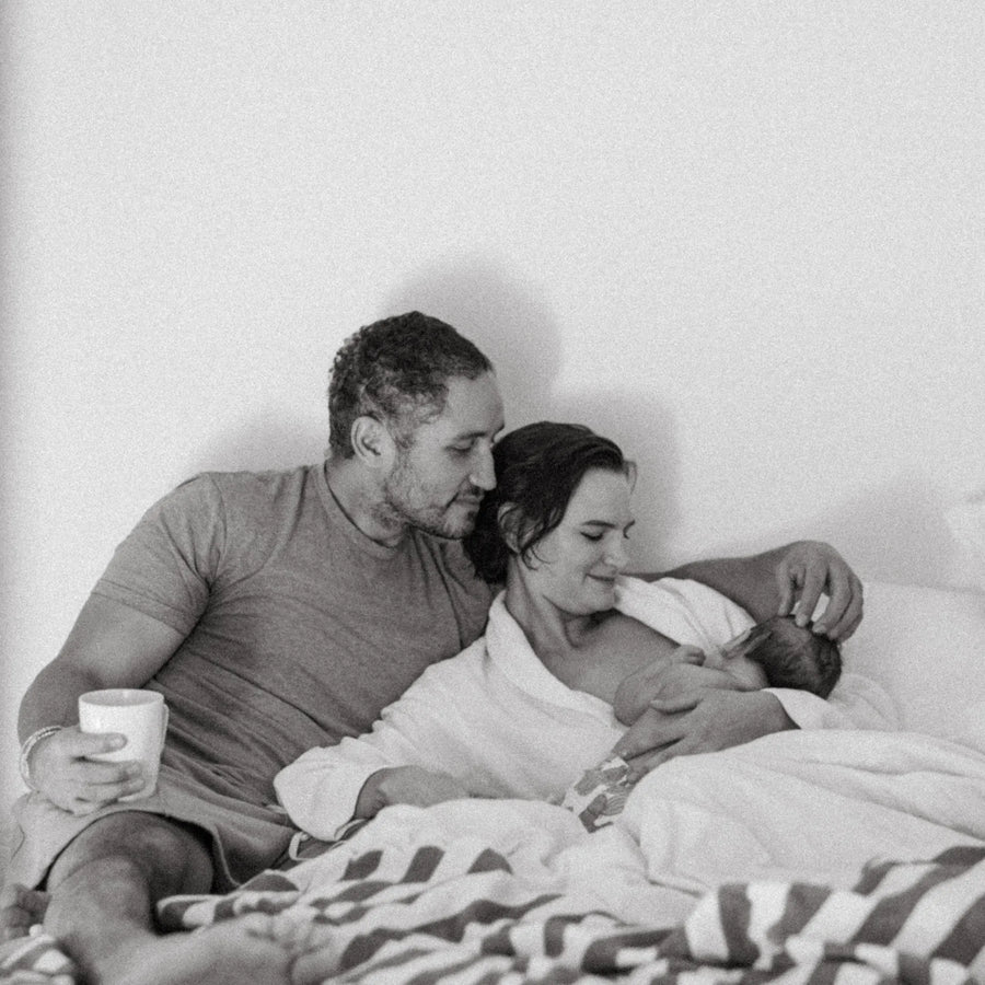 Ein Mann und eine Frau im Bett, während die Frau stillt