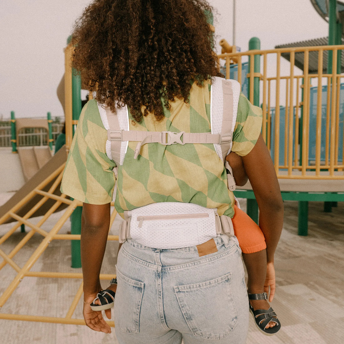 Dos d’une personne tenant un bébé dans un porte-bébé