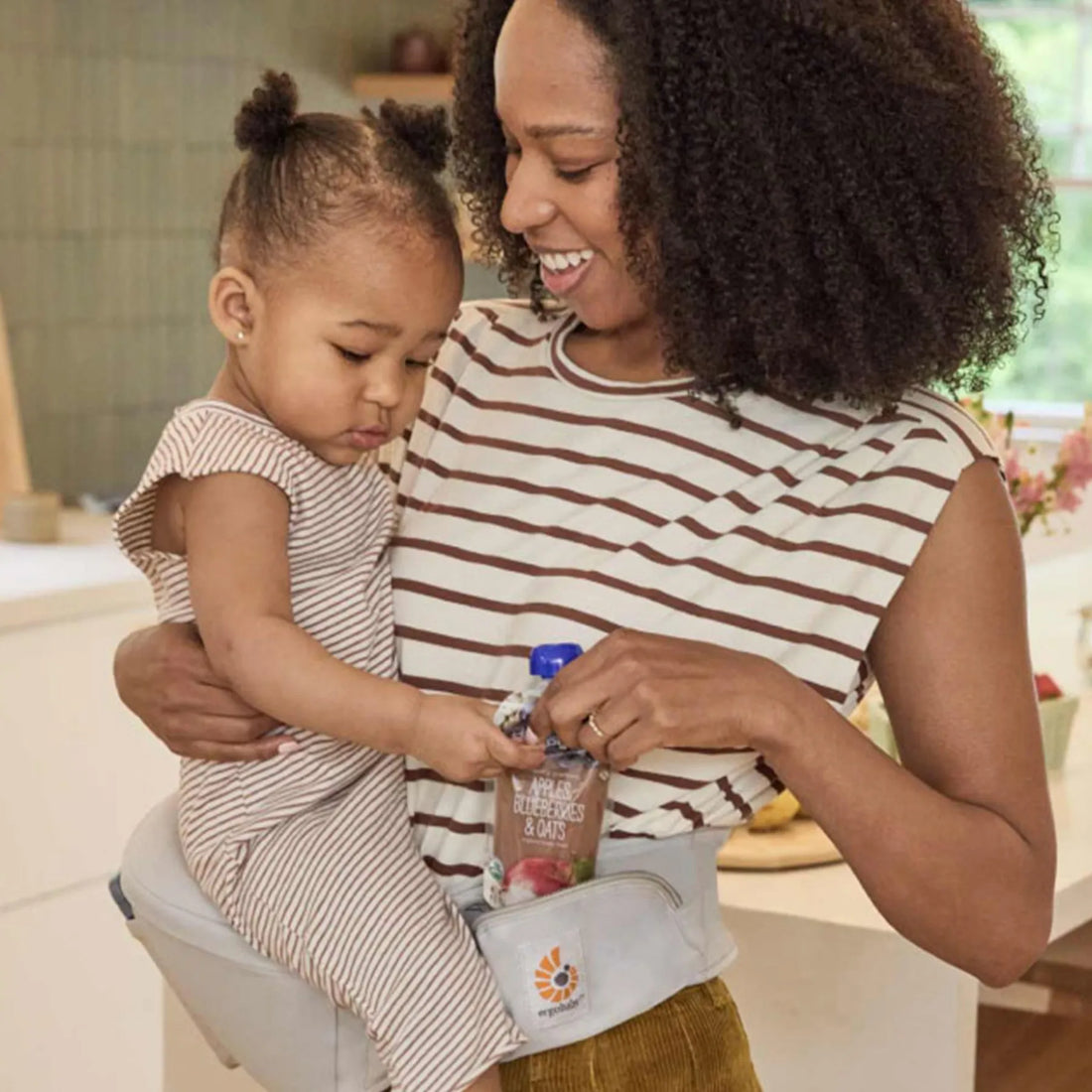 Frau, die ein Baby in einem Hüftsitz auf der Hüfte trägt