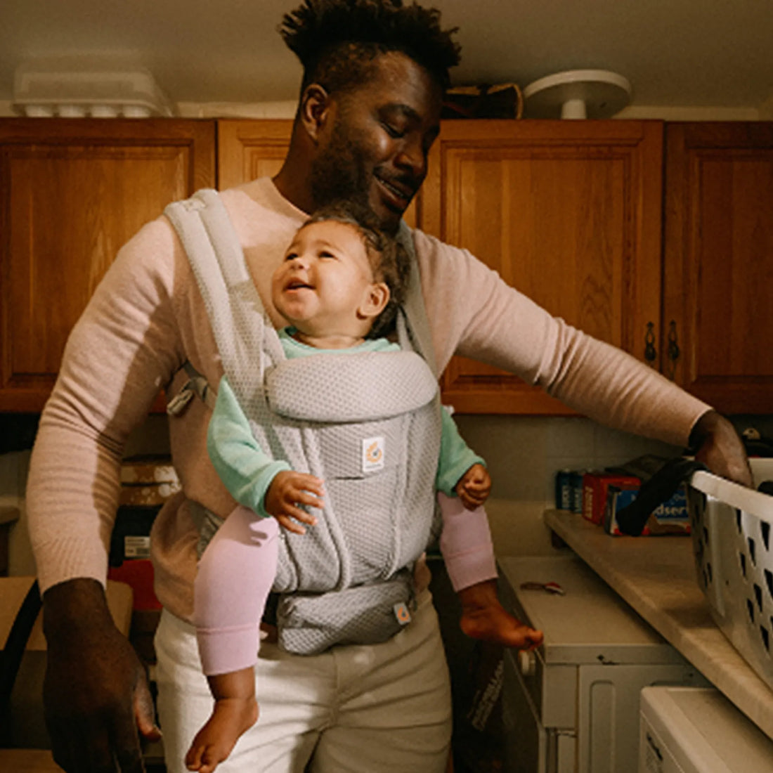 Ein Mann, der ein Baby in einer Babytrage hält, das nach vorne schaut