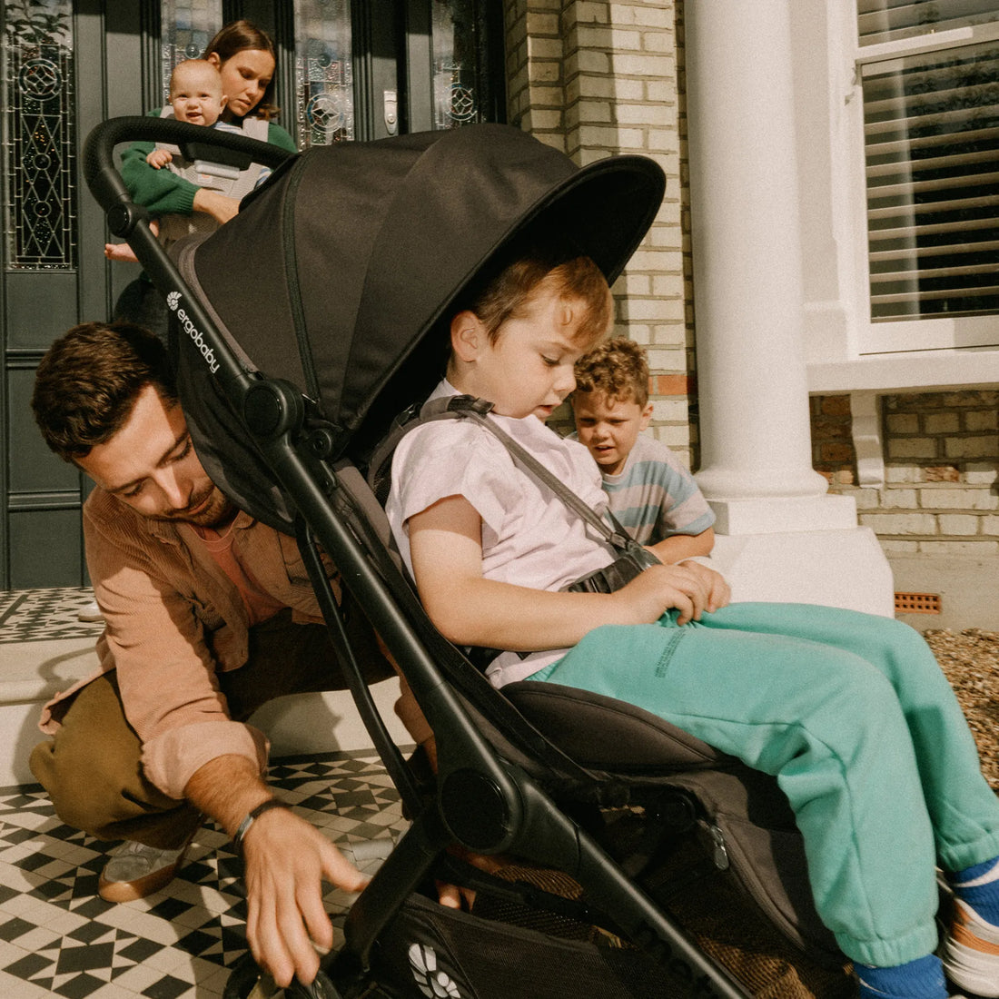 Ein Mann schiebt ein Kleinkind im Kinderwagen, während Familienmitglieder zuschauen