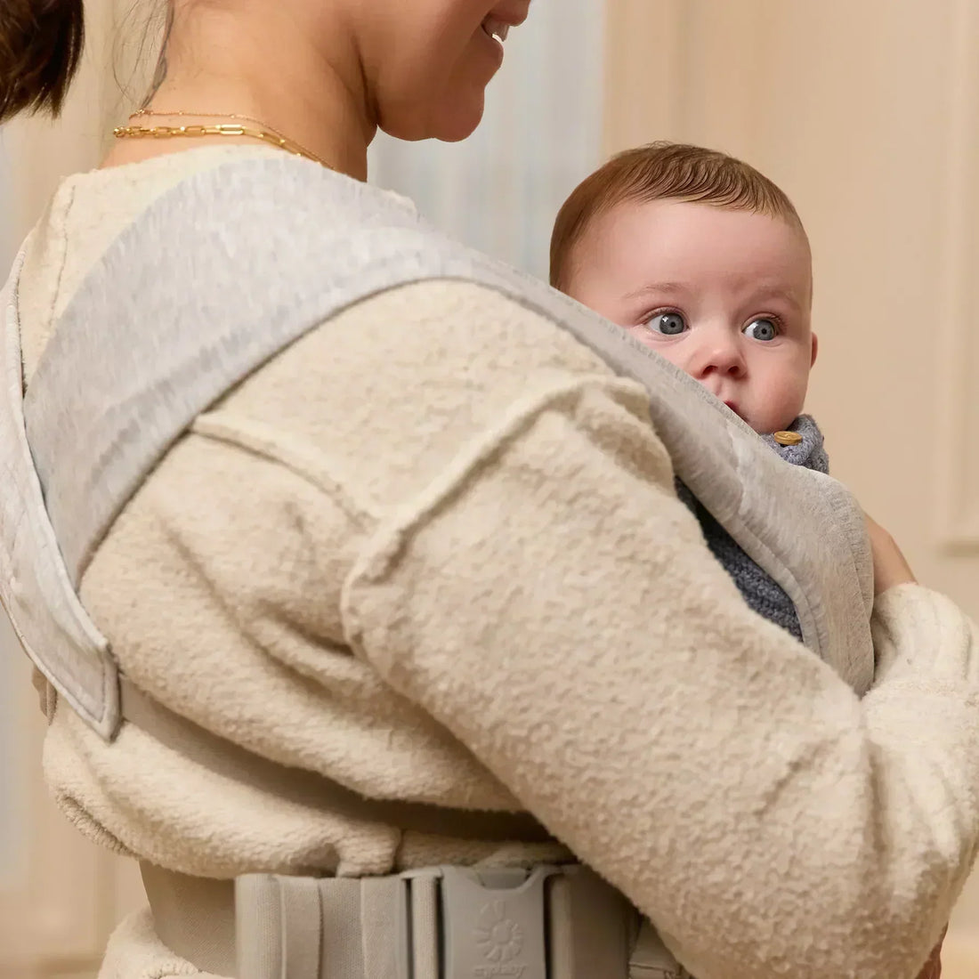 Frau mit Baby in einem hellgrauen Babytrage