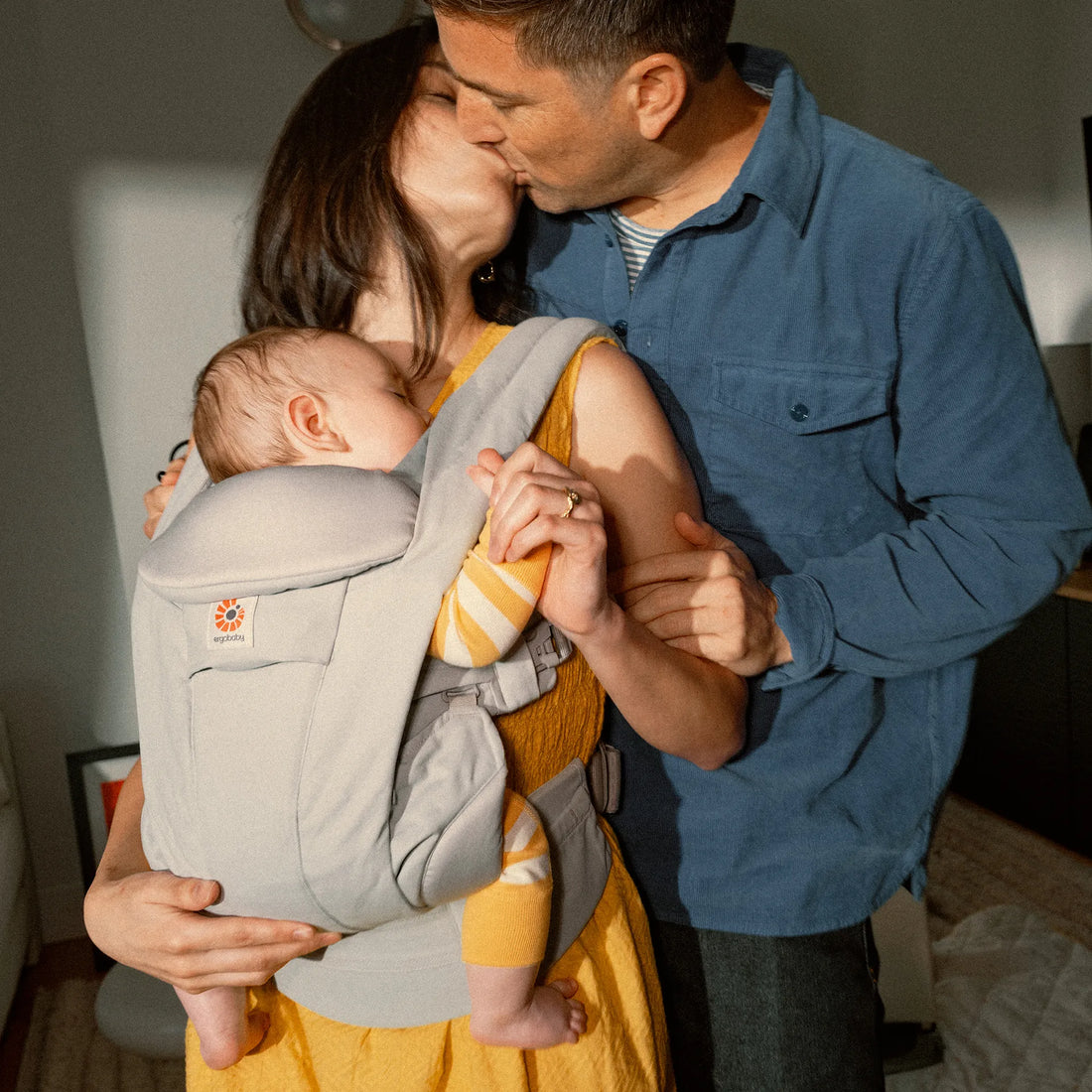 Eine Frau, die ein Baby in einer Babytrage hält und einen Mann Babytrage