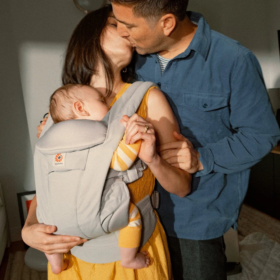 Eine Frau, die ein Baby in einer Babytrage hält und einen Mann Babytrage