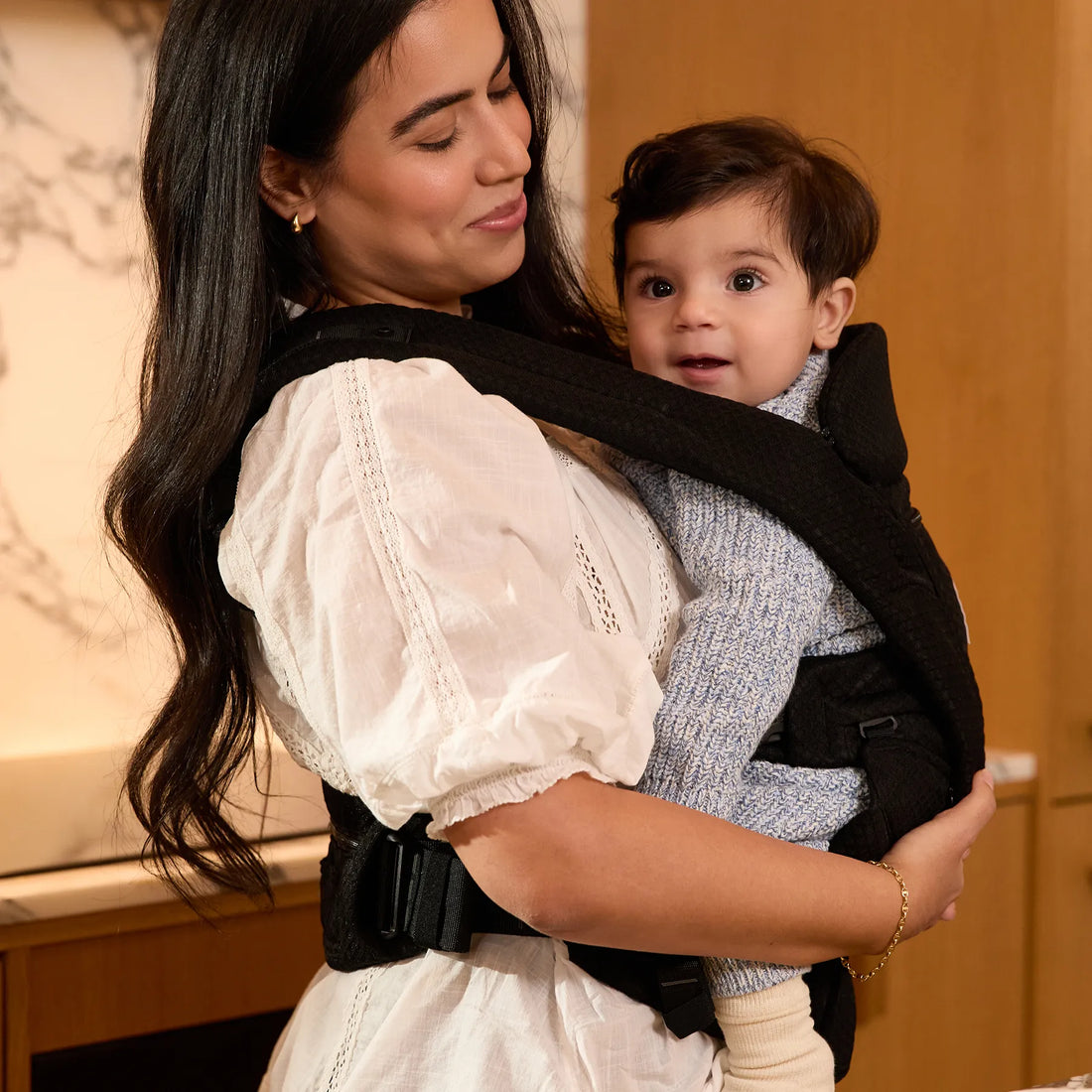 Donna con un bambino in un marsupio nero