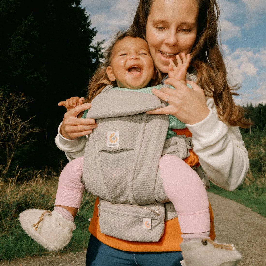 Frau, die ein Baby in einem grauen Babytrage hält
