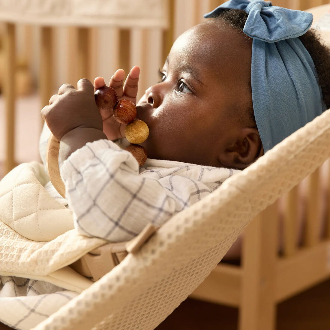 En bebis med ett blått hårband i en babysitter