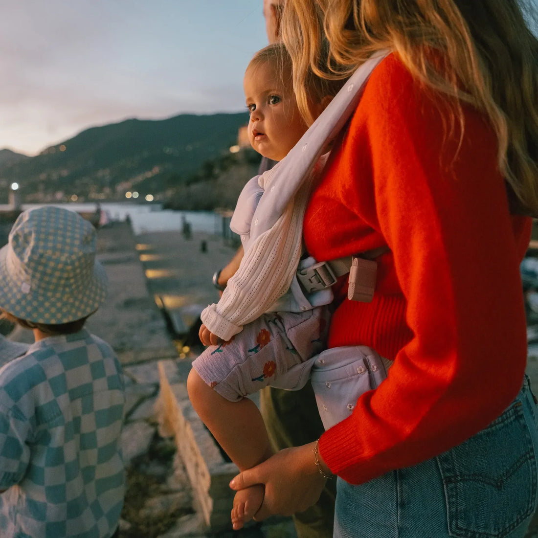 Frau, die Babytrage ein Baby in einem Babytrage hält, wobei das Baby nach vorne schaut
