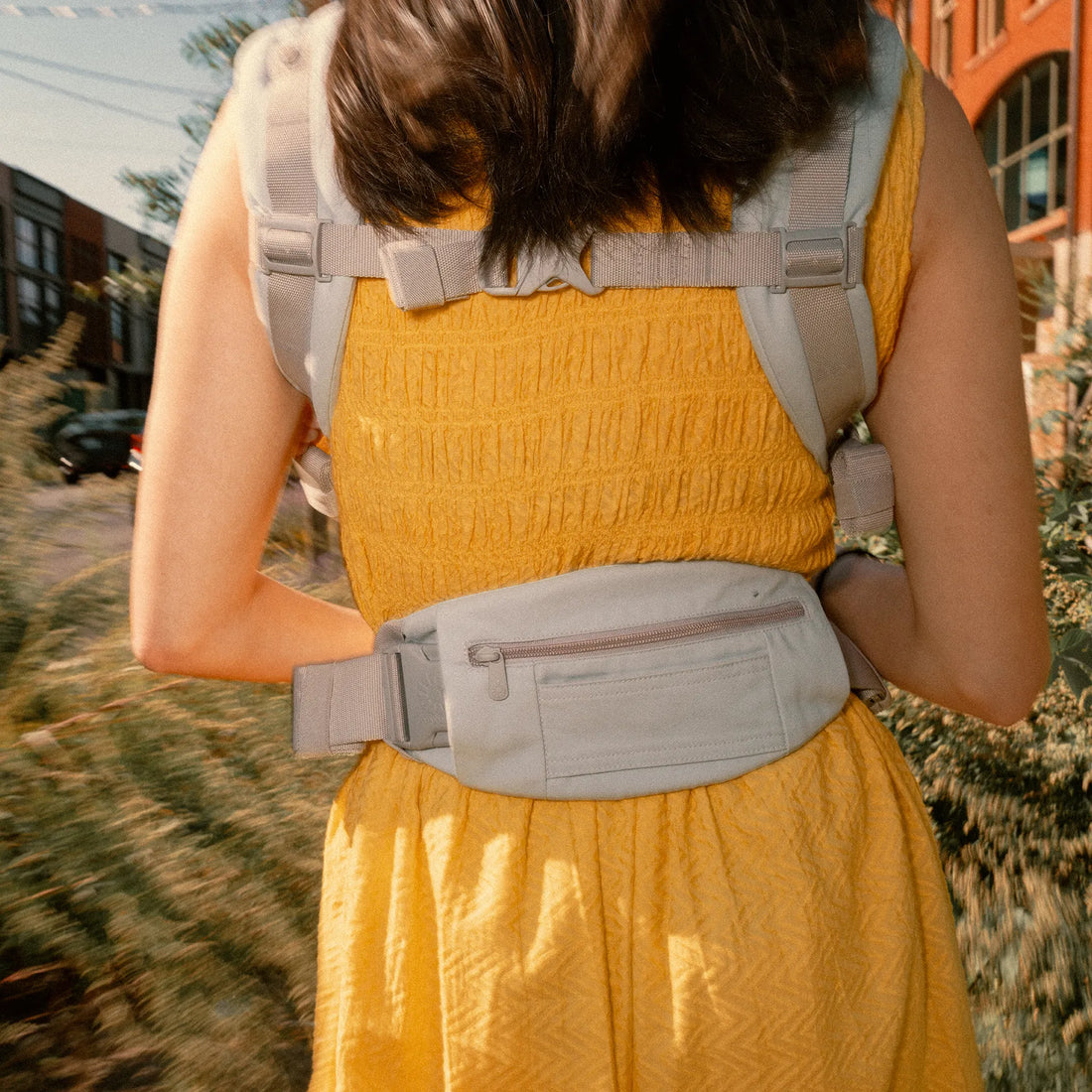 Rückenansicht einer Frau, die eine Babytrage trägt