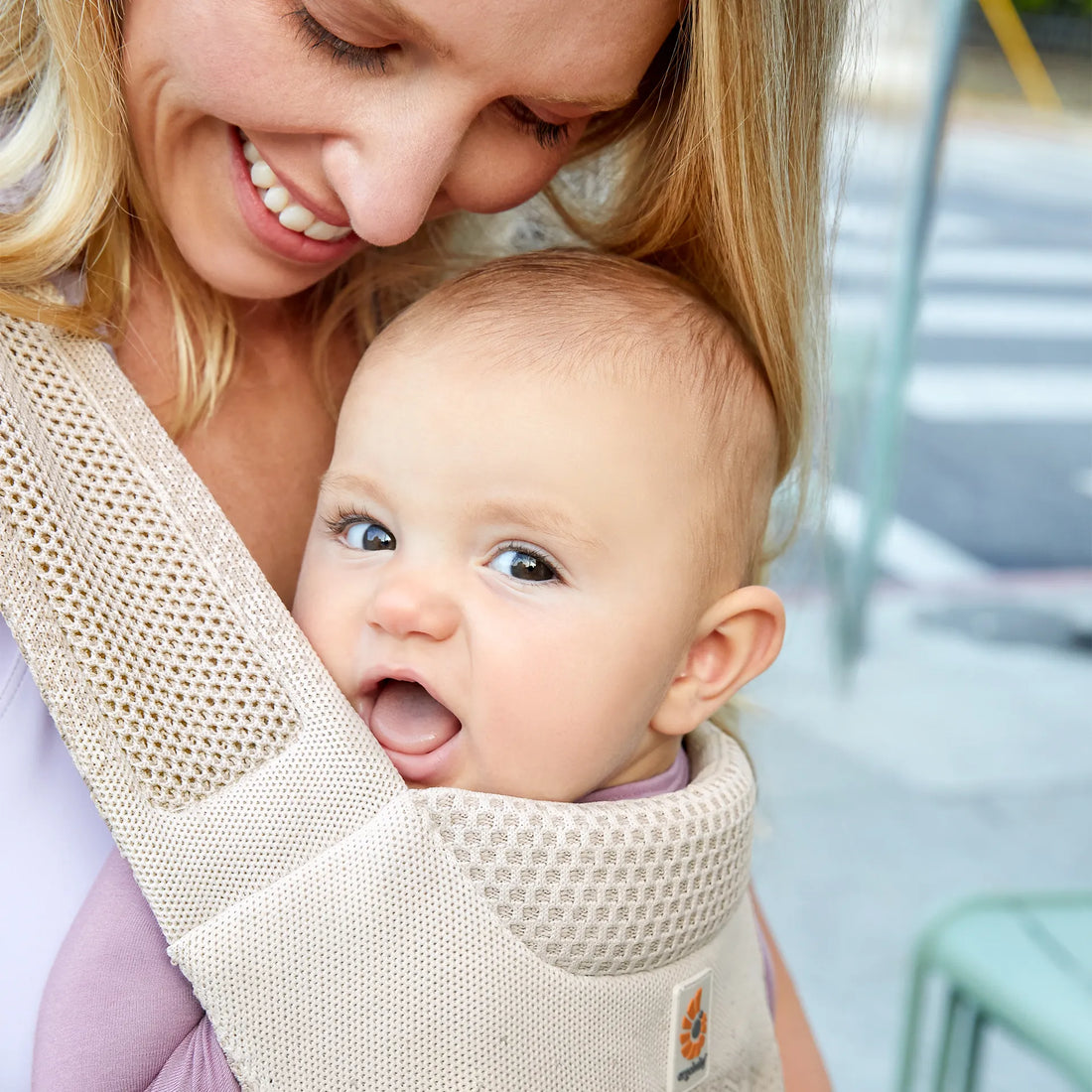 Frau, die ein Baby in einer beigen Babytrage hält