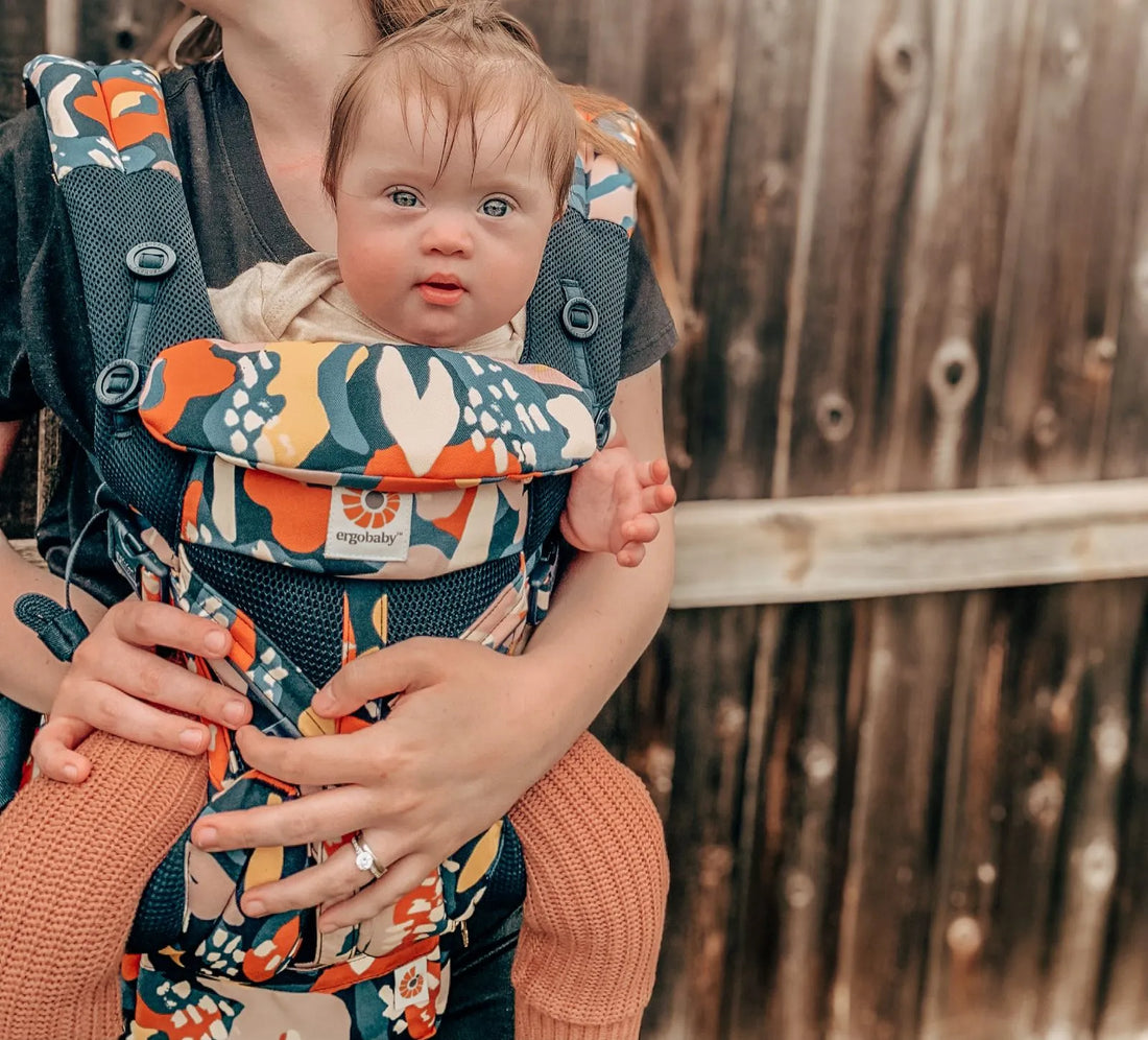 Frau, die ein Baby in einem gemusterten Babytrage hält