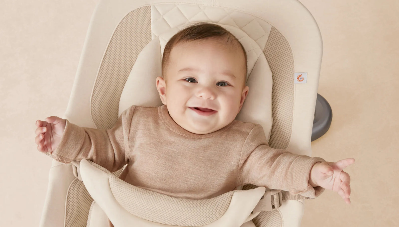 Ein Baby in einem beigen Hochstuhl mit einem lächelnden Gesichtsausdruck