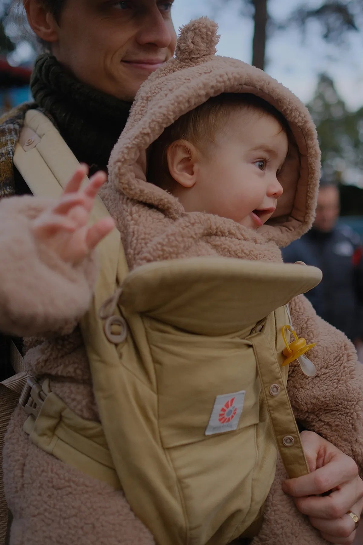 Ein Baby in einer beigen omni classic Babytrage durch den Wald